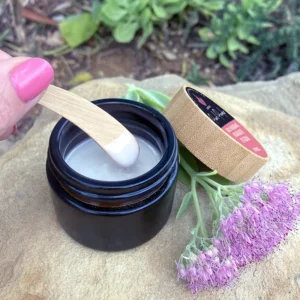 Castor oil and pearl powder eye serum in amber glass jar with bamboo spatula applying creamy natural serum, botanical skincare product for under eye nourishment and regeneration