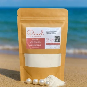 A kraft stand-up pouch of pure freshwater Pearl Powder (100g–500g) photographed on a sandy beach with a small pile of loose pearl powder and four pearls at the base, symbolizing purity and natural beauty benefits.