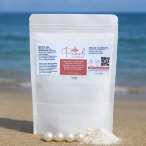 A kraft stand-up pouch of pure freshwater Pearl Powder (100g–500g) photographed on a sandy beach with a small pile of loose pearl powder and four pearls at the base, symbolizing purity and natural beauty benefits.