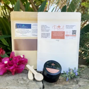 Pearl powder and cocoa powder with castor oil pearl eye serum — natural beauty ritual bundle photographed in a garden setting.